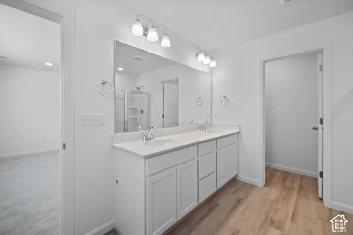 Double-sink vanity with white cabinetry, solid-surface countertop, full-width mirror, and dual chrome-finish fixtures