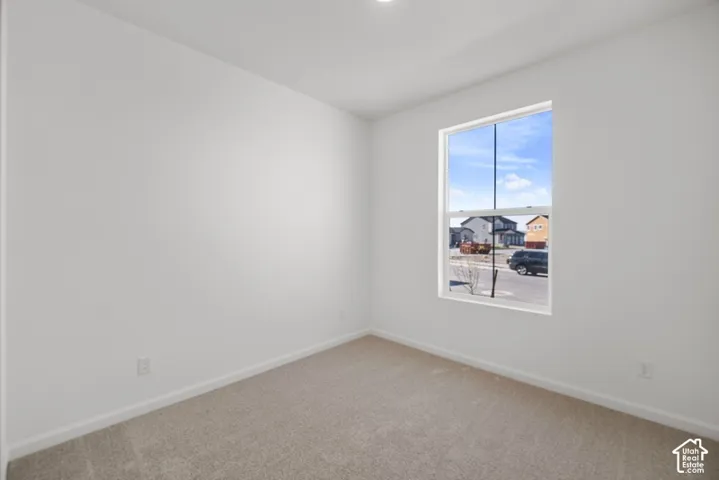Neutral-toned interior space featuring wall-to-wall carpeting and a single-hung window with high-contrast framing