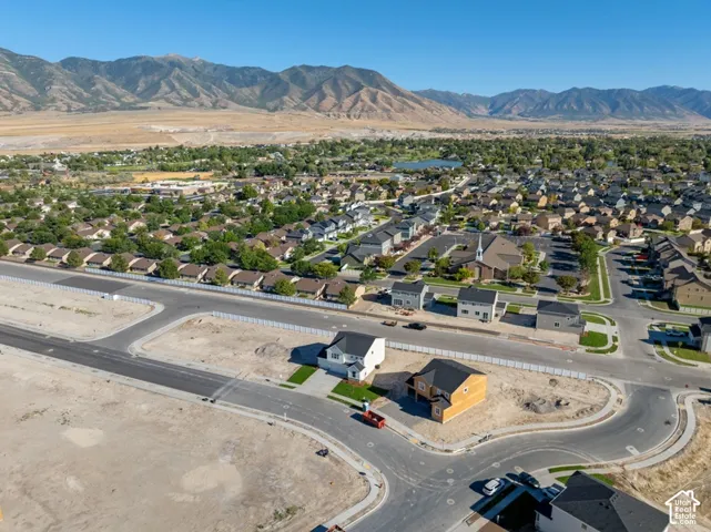 Aerial perspective featuring newly constructed residential dwellings with asphalt shingle roofing, concrete driveways, and expansive mountain range backdrop
