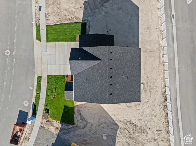 Aerial view featuring a multi-gabled asphalt shingle roof, a concrete driveway, and a white privacy fence along the perimeter