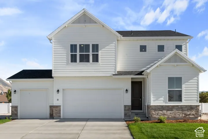 Two-story residence featuring horizontal siding, a stone veneer foundation, multi-gabled roofline, three-car garage, and a dark-toned entry door