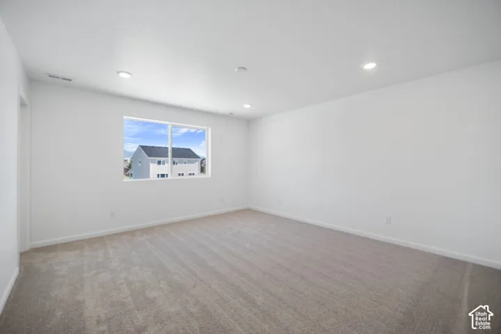 Neutral-toned carpeting, recessed ceiling lighting, and a single sliding window