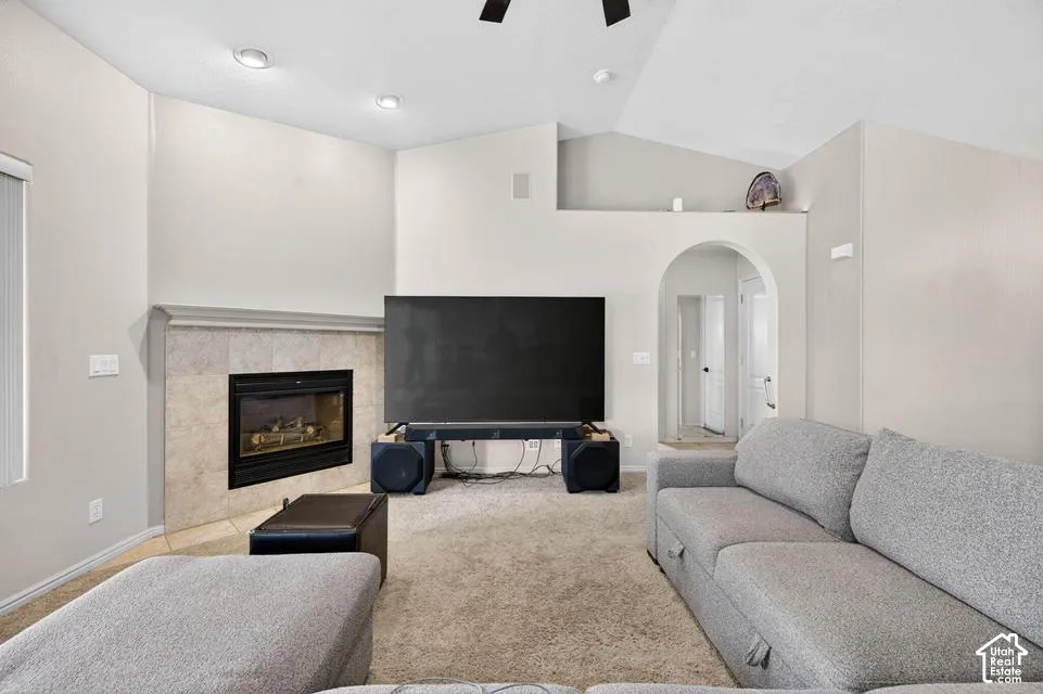 Living area featuring a vaulted ceiling, recessed lighting, stone-surround fireplace with a mantel, and a decorative arched entryway