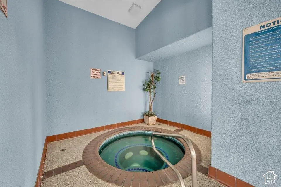 Indoor spa featuring a circular basin, tiled surround, and stainless steel grab bar