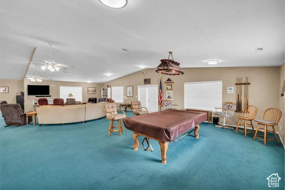 Spacious room featuring a vaulted ceiling, multiple ceiling fans, recessed lighting, and a stained-glass chandelier