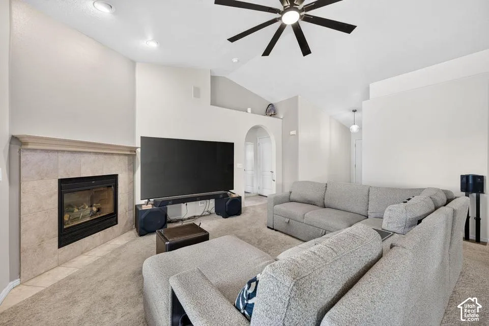 Vaulted ceilings featuring a central multi-blade ceiling fan, recessed lighting, and a stone-surround fireplace with a wooden mantel