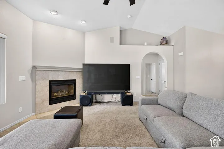 Living area featuring a vaulted ceiling, recessed lighting, stone-surround fireplace with a mantel, and a decorative arched entryway