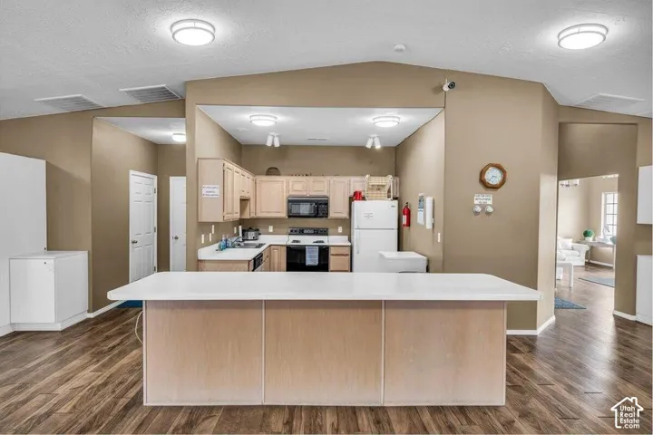 Kitchen featuring a center island, wood-finish cabinetry, solid-surface countertops, and wood-finish flooring