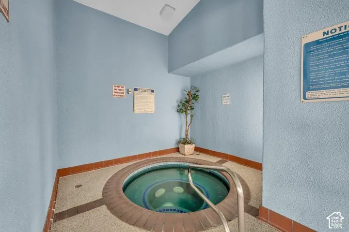 Indoor spa featuring a circular basin, tiled surround, and stainless steel grab bar