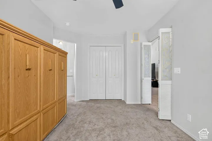 Built-in wood-finish cabinetry, neutral carpeting, and louvered closet doors with decorative glass panels