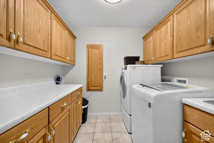 Laundry area featuring custom oak cabinetry, laminate countertops, a flush-mount light fixture, and tile flooring