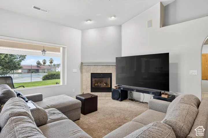 Vaulted ceilings, corner fireplace with tile surround, large picture window, and recessed lighting