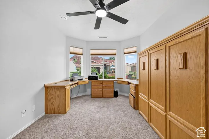Built-in oak cabinetry with integrated desk workspace, bay window configuration, and matte black ceiling fan