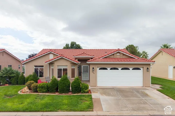 Single-story residence featuring a tile roof, stucco exterior, two-car garage with arched window detailing, and manicured landscaping