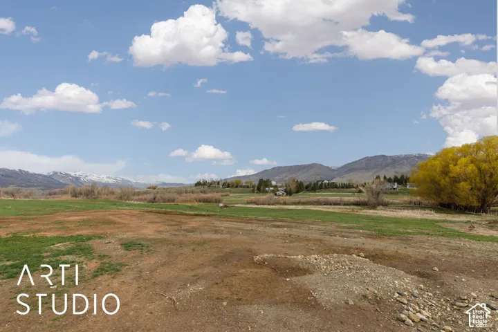Expansive land parcel featuring open terrain, natural grasses, mature trees, and mountain backdrops