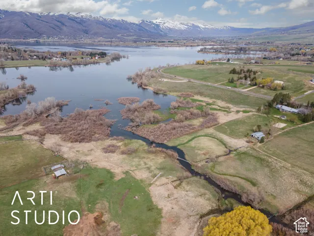Aerial perspective featuring expansive acreage, natural water frontage, and mountain backdrop