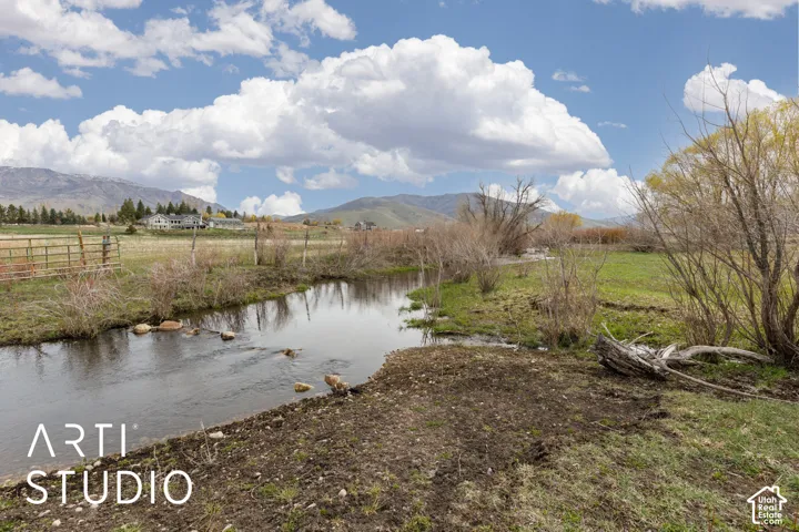 Natural creek frontage featuring grassy banks, mature trees, and mountainous terrain