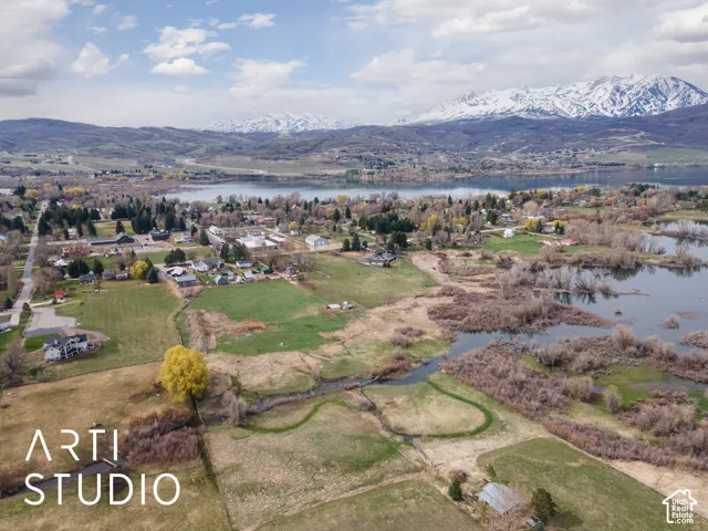 Aerial perspective featuring expansive acreage, natural water frontage, and mountain backdrops