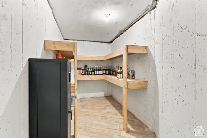 Storage room with concrete walls, wood-finish flooring, and multi-tier wooden shelving units