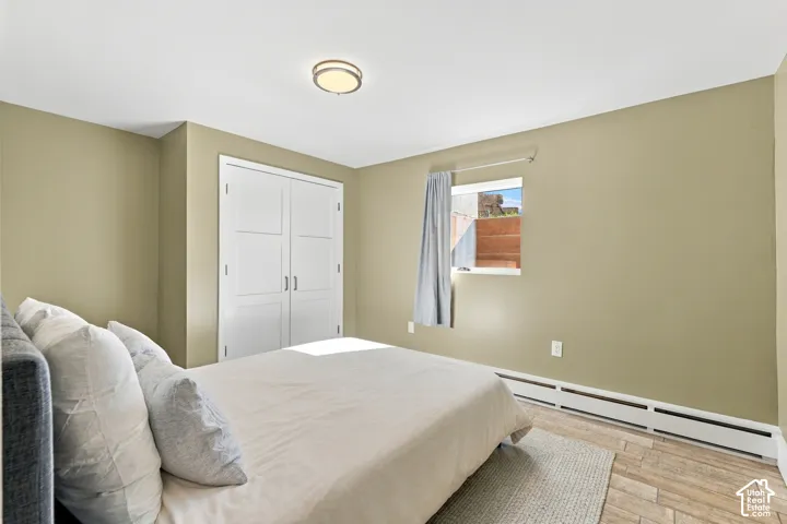 Room featuring wood-finish flooring, dual-panel closet doors, and a window with exterior masonry