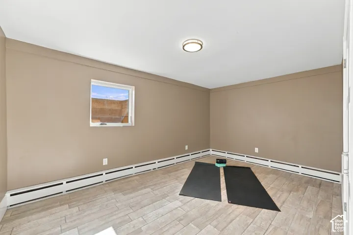 Neutral-toned room featuring wood-finish flooring, a single-pane window, and a flush-mount circular ceiling light fixture