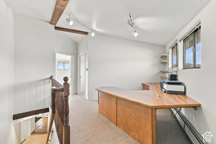 Built-in wood desk, exposed wood ceiling beams, track lighting, and wood balustrade railing