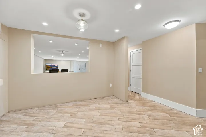 Interior space featuring wood-finish tile flooring, recessed lighting, a decorative pendant light, a recessed wall opening, and a multi-panel door