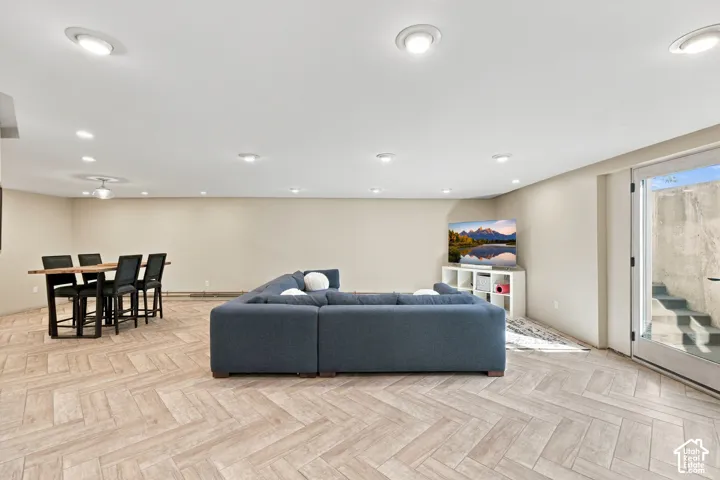 Open-concept interior featuring neutral wall tones, herringbone-patterned flooring, and recessed ceiling lighting throughout