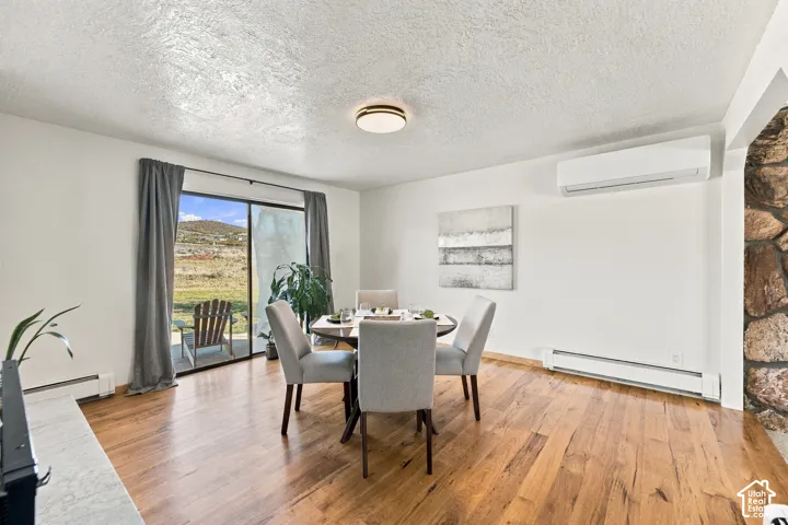 Wood-finish flooring, stone masonry accent wall, sliding glass door, wall-mounted ductless climate control system, and flush-mount lighting