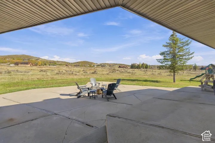 Covered concrete patio with open-air access to expansive exterior grounds and mountain scenery