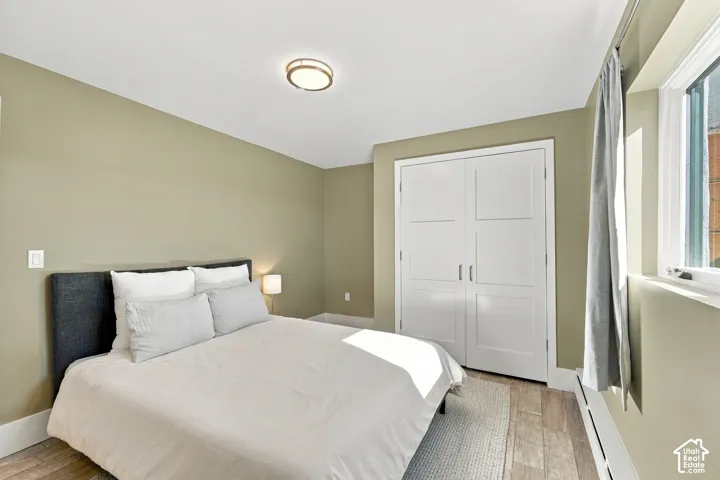 Room featuring wood-finish flooring, a double-door closet with shaker-style detailing, and a flush-mount circular ceiling light fixture