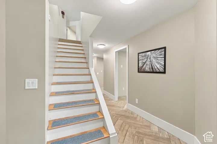 Staircase featuring wood-finish treads and white stringers with herringbone-patterned tile flooring