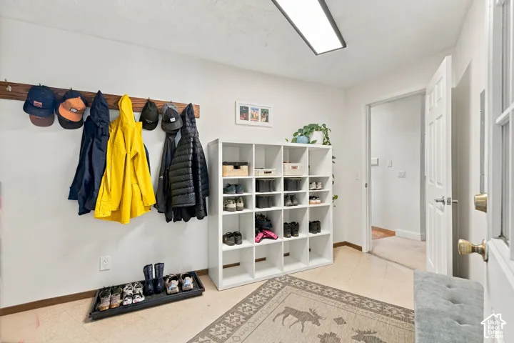 Mudroom featuring tile flooring, wall-mounted wooden coat rack, and recessed ceiling lighting