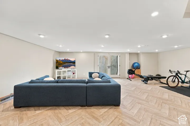 Open-concept area featuring herringbone-patterned wood-finish flooring, recessed lighting, and double-glass doors