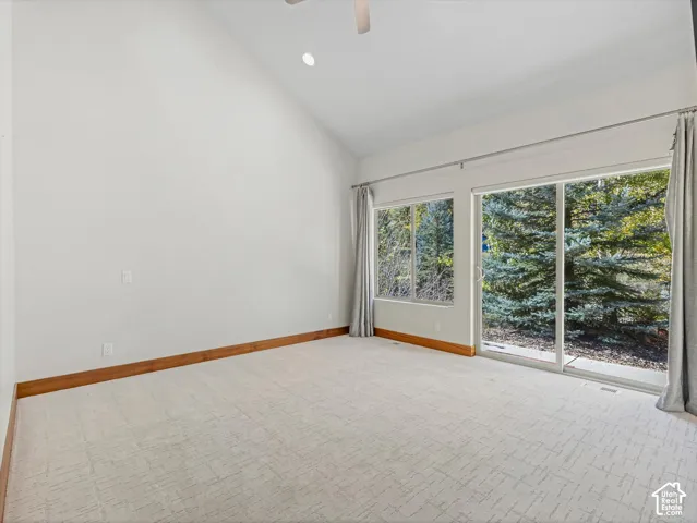 Vaulted ceilings, large sliding glass doors, neutral carpeting, and wood-finish trim accents