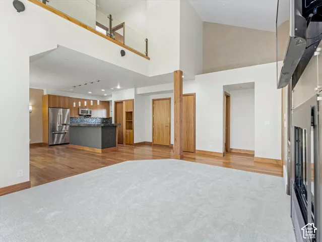 Vaulted ceilings with mezzanine overlook, wood-finish flooring, kitchen island with stone countertop, stainless steel appliances, and integrated fireplace