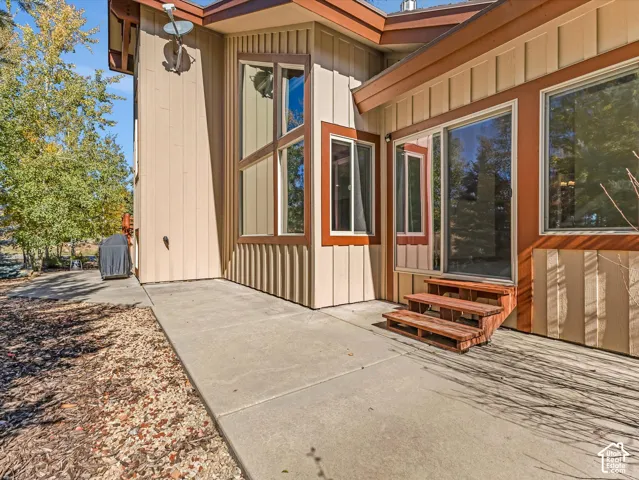 Vertical wood siding exterior featuring expansive multi-pane windows, a concrete patio, and a set of wooden exterior stairs