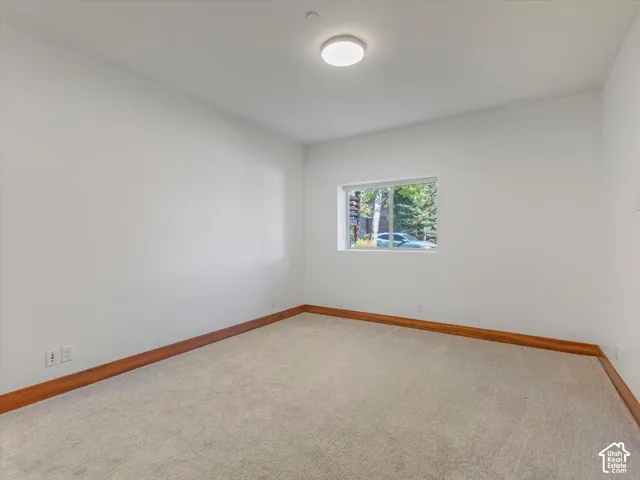 Neutral-toned carpeting, wood-finish trim, single-pane window, and recessed LED ceiling lighting