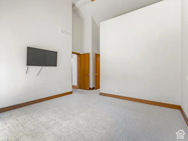 Vaulted ceiling, textured carpeting, and natural wood-tone interior doors