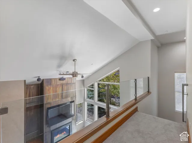 Vaulted ceilings with recessed lighting, glass panel balcony railing with wood-finish cap, and multi-story windows