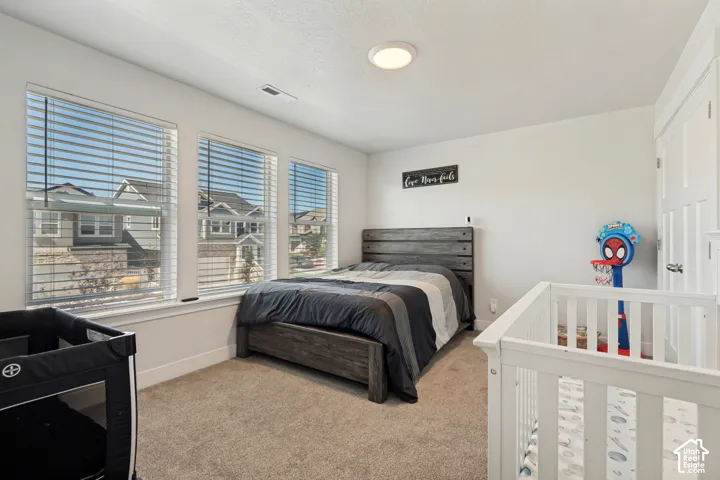 Room featuring three large windows with horizontal blinds, neutral-toned carpet, and a flush-mount ceiling light