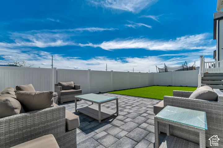 Paver patio area with artificial turf, bordered by a white privacy fence