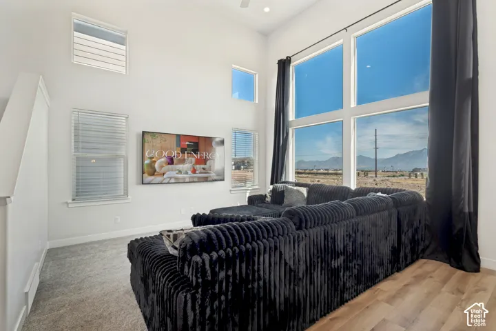 Vaulted ceiling with recessed lighting, expansive picture windows, wood-finish flooring, and carpeted area