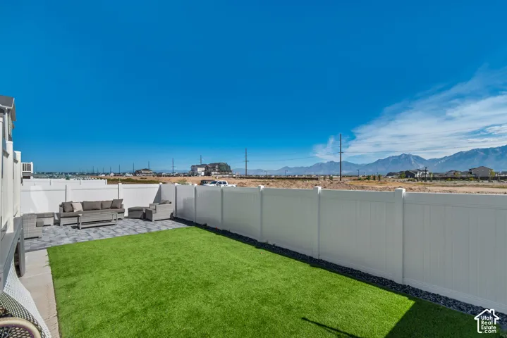 Enclosed backyard featuring a paver patio area, artificial turf, and a perimeter fence