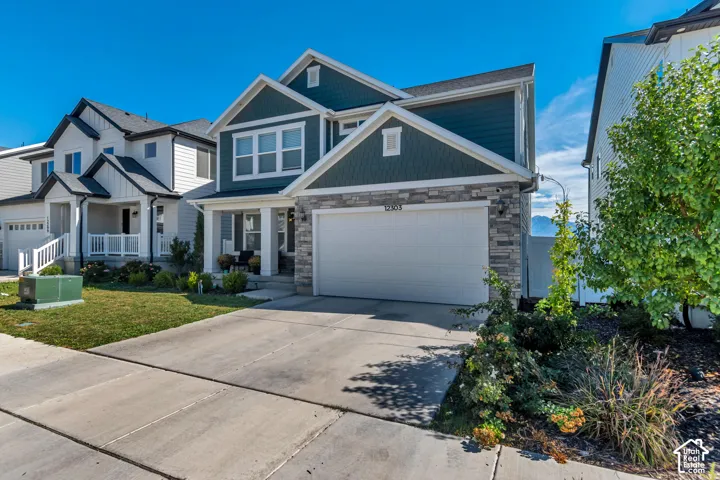 Contemporary multi-story residence featuring a two-car garage, stone and siding exterior, and a covered front porch