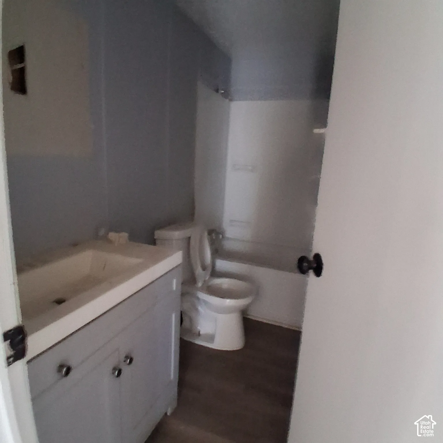 Bathroom featuring a vanity with an integrated sink, wood-finish flooring, and a tub-shower combination with a surround