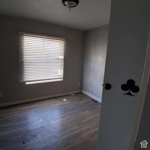 Room featuring wood-finish flooring, a large window with horizontal blinds, and a circular flush-mount ceiling light fixture