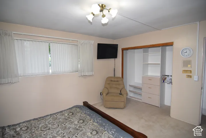 Owner's Interior room featuring a large window with vertical blinds, ceiling-mounted multi-bulb light fixture, and built-in closet storage with integrated shelving and drawers