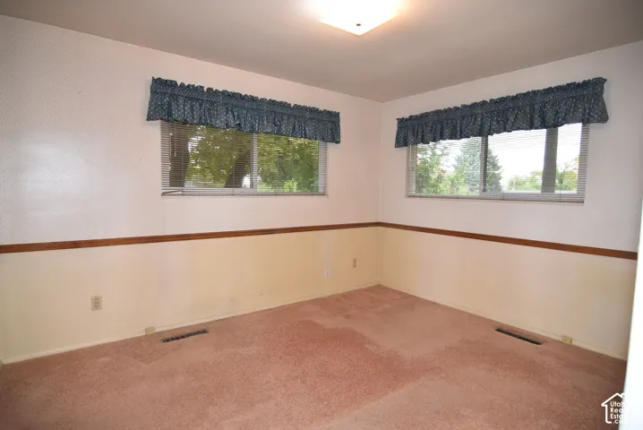 Bedroom  #1 featuring dual-aspect sliding windows, wood-trimmed chair rail molding, and neutral wall surfaces with overhead flush-mount lighting