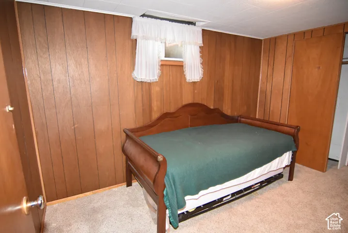 Bedroom #3 featuring wood-paneled walls, neutral carpeting, a built-in closet, and a rectangular window